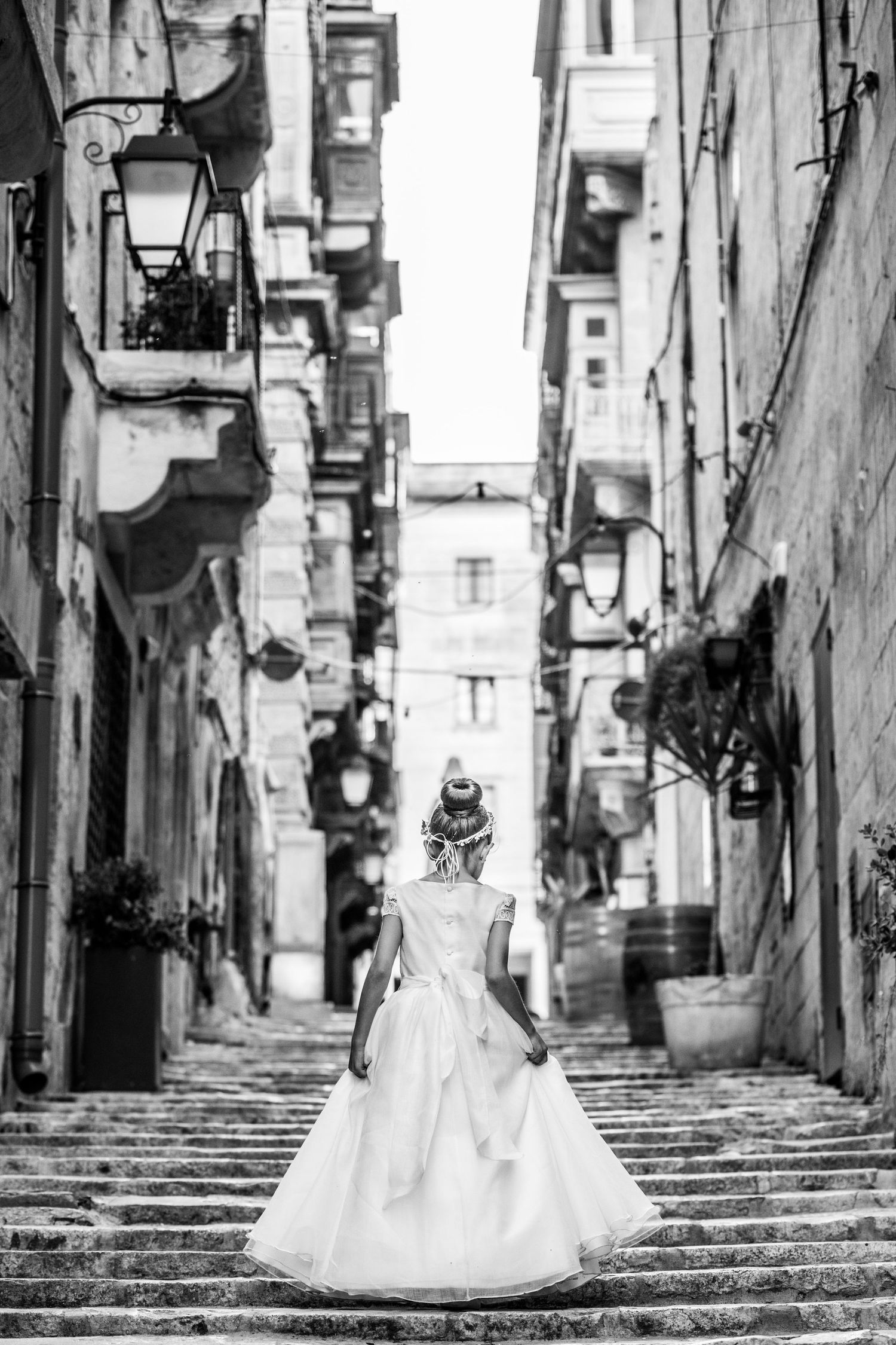 Black and white photos of a white dress flowing down historic stone steps in an old European alley.