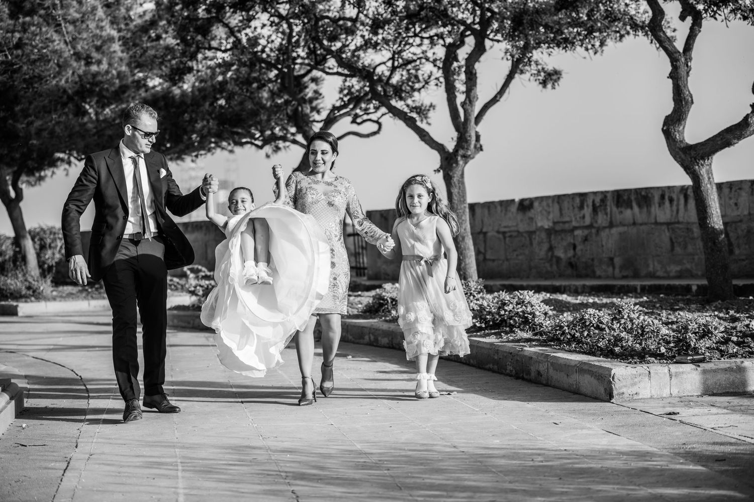 People walking and playing together outdoors in formal attire during a celebration.