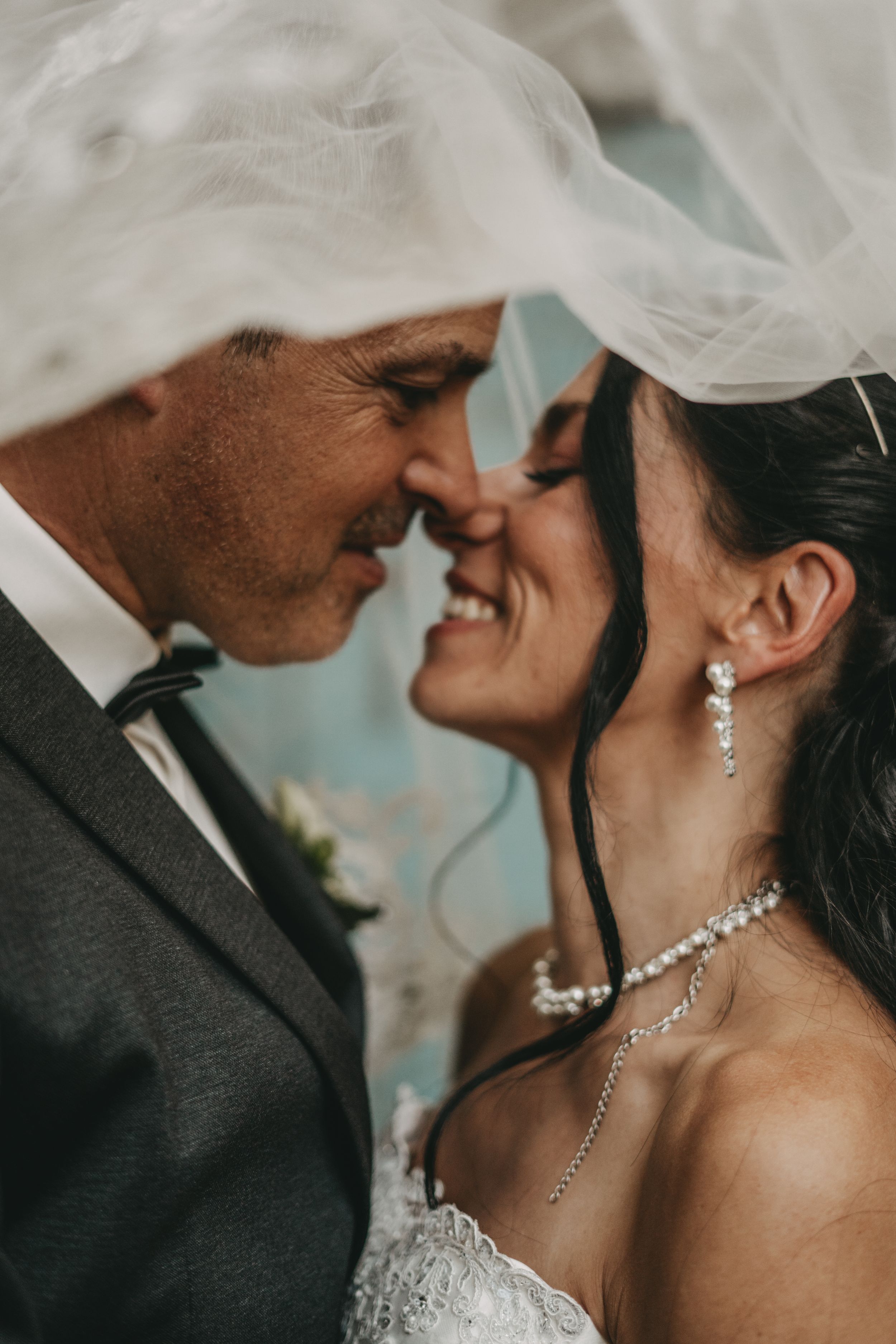Intimate wedding portrait showing tender moment between newlyweds with bride wearing delicate jewelry.