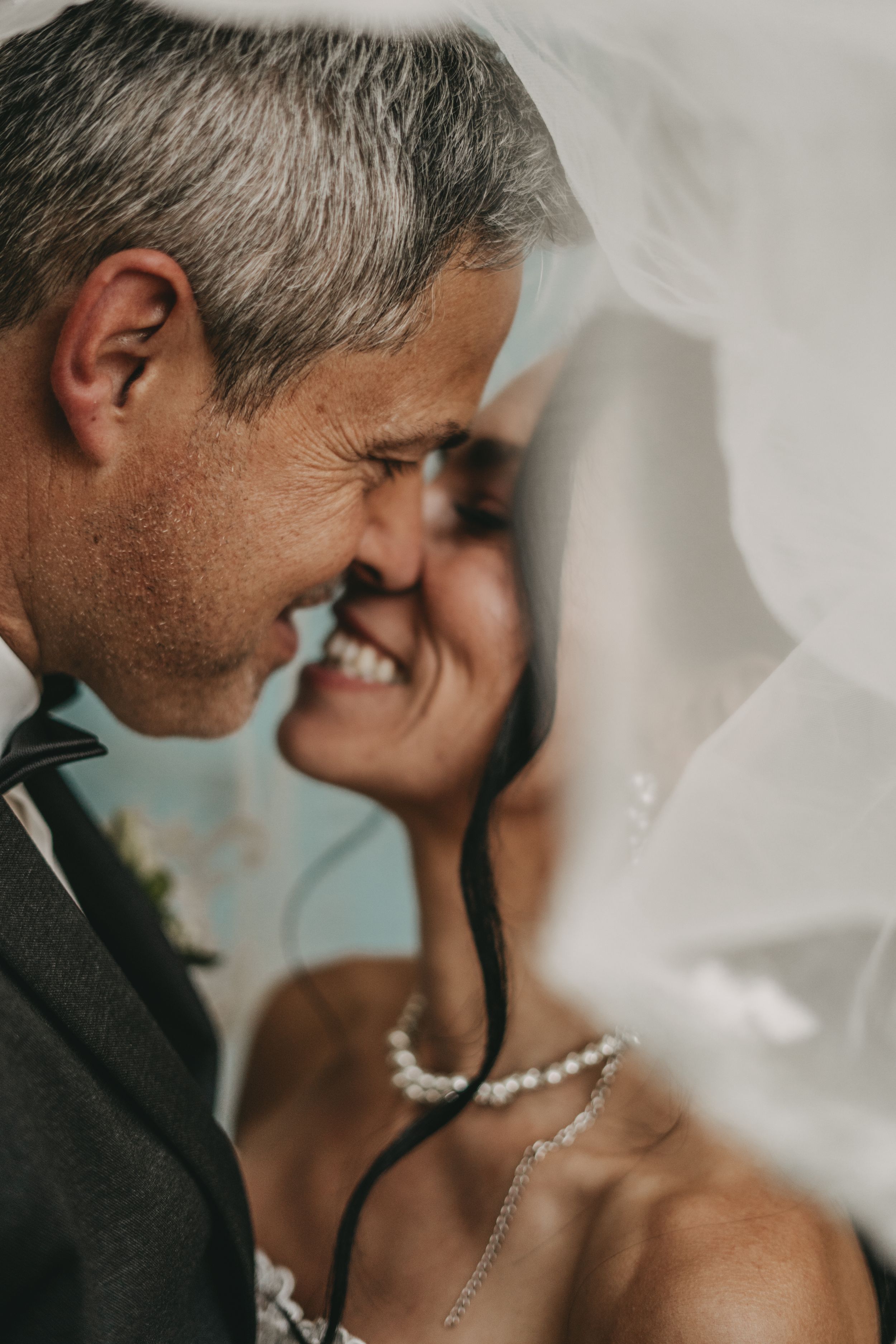 Artistic black and white close-up of newlyweds sharing a romantic moment under a veil.