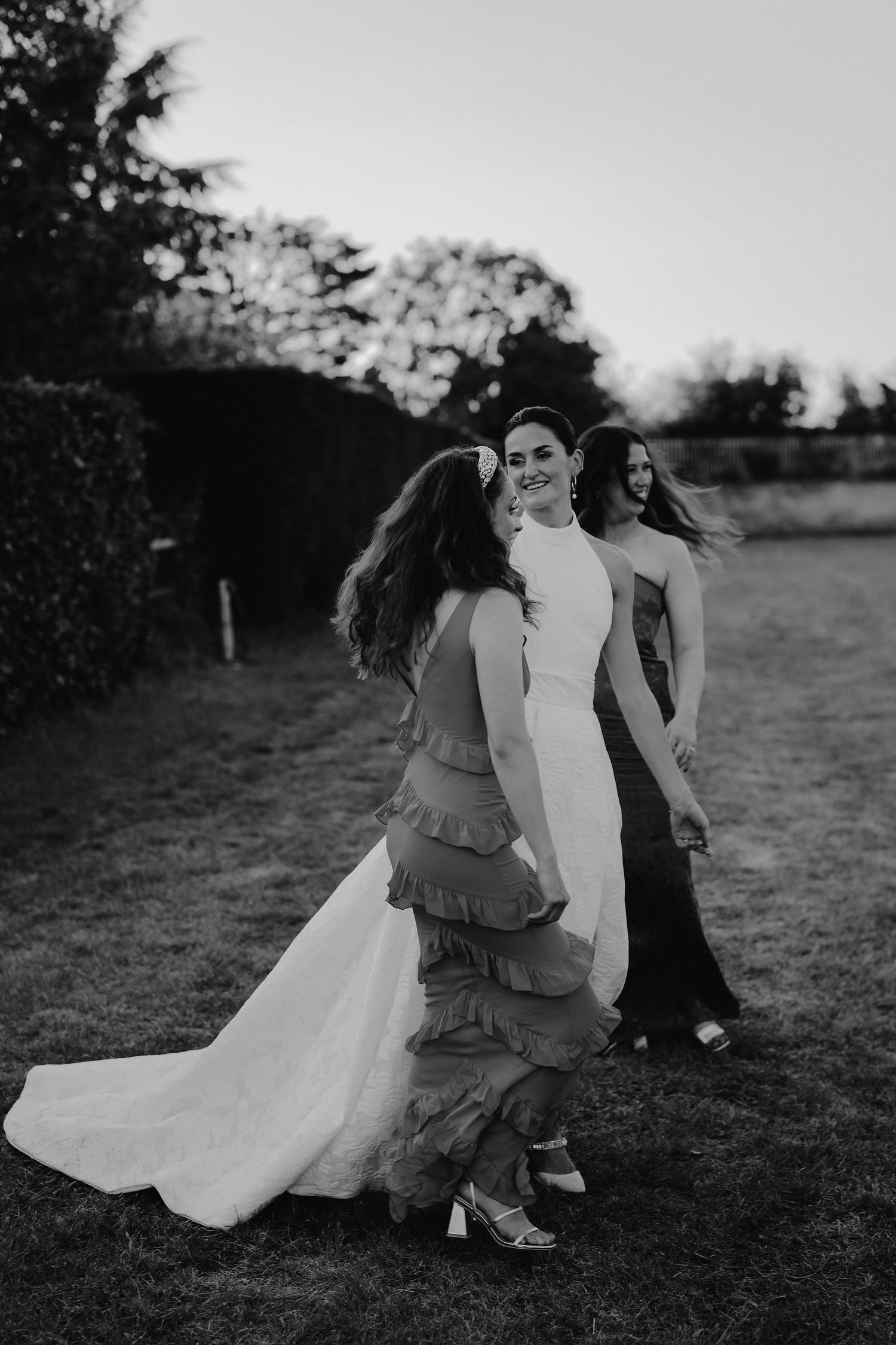 bride and friends smiling on lawn at marquee wedding in islip in oxfordshire