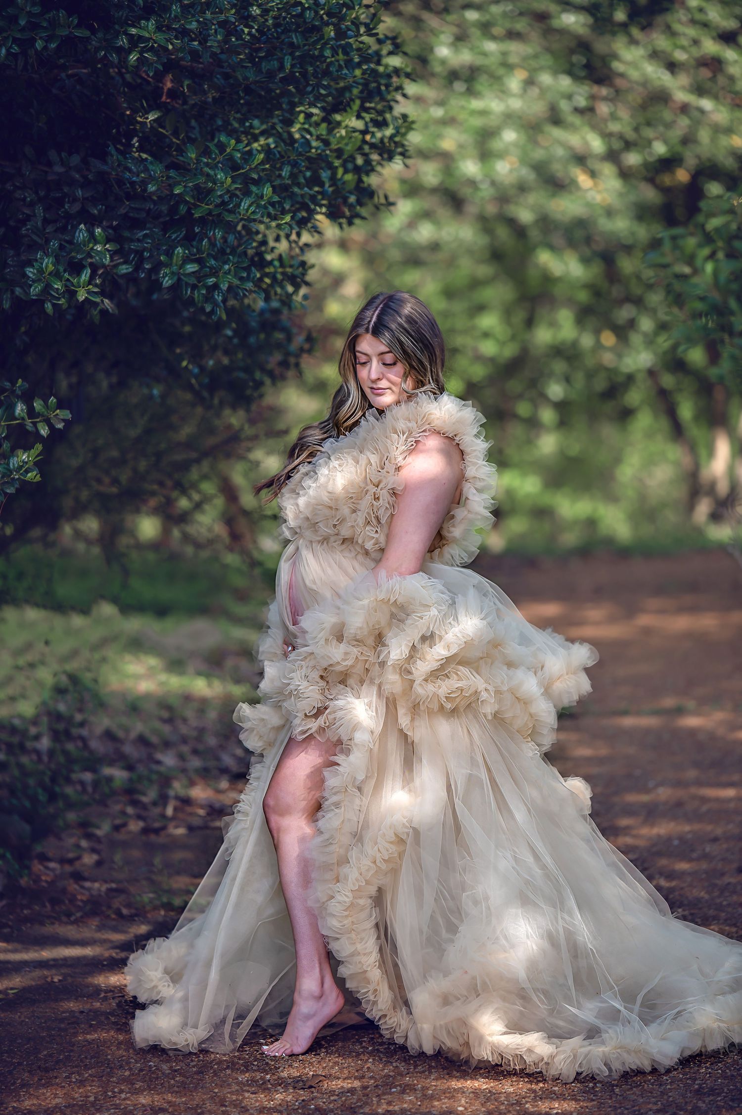 Whimsical forest photography featuring a flowing champagne tulle gown in dappled sunlight.