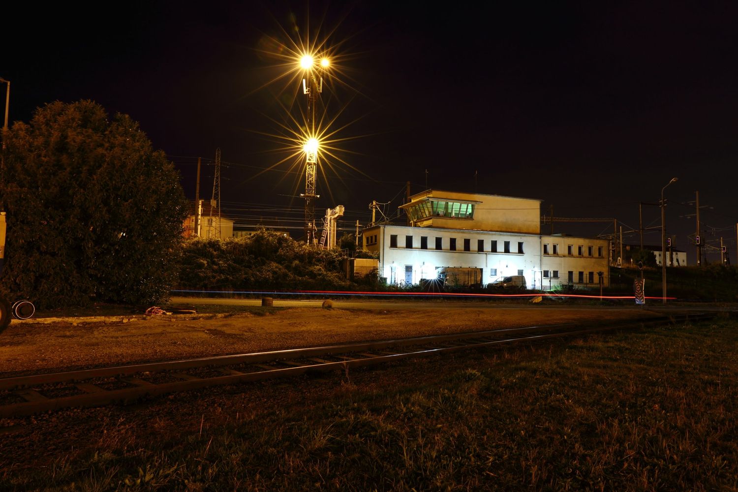 Illuminated industrial building at night with street lamps casting star-shaped light.