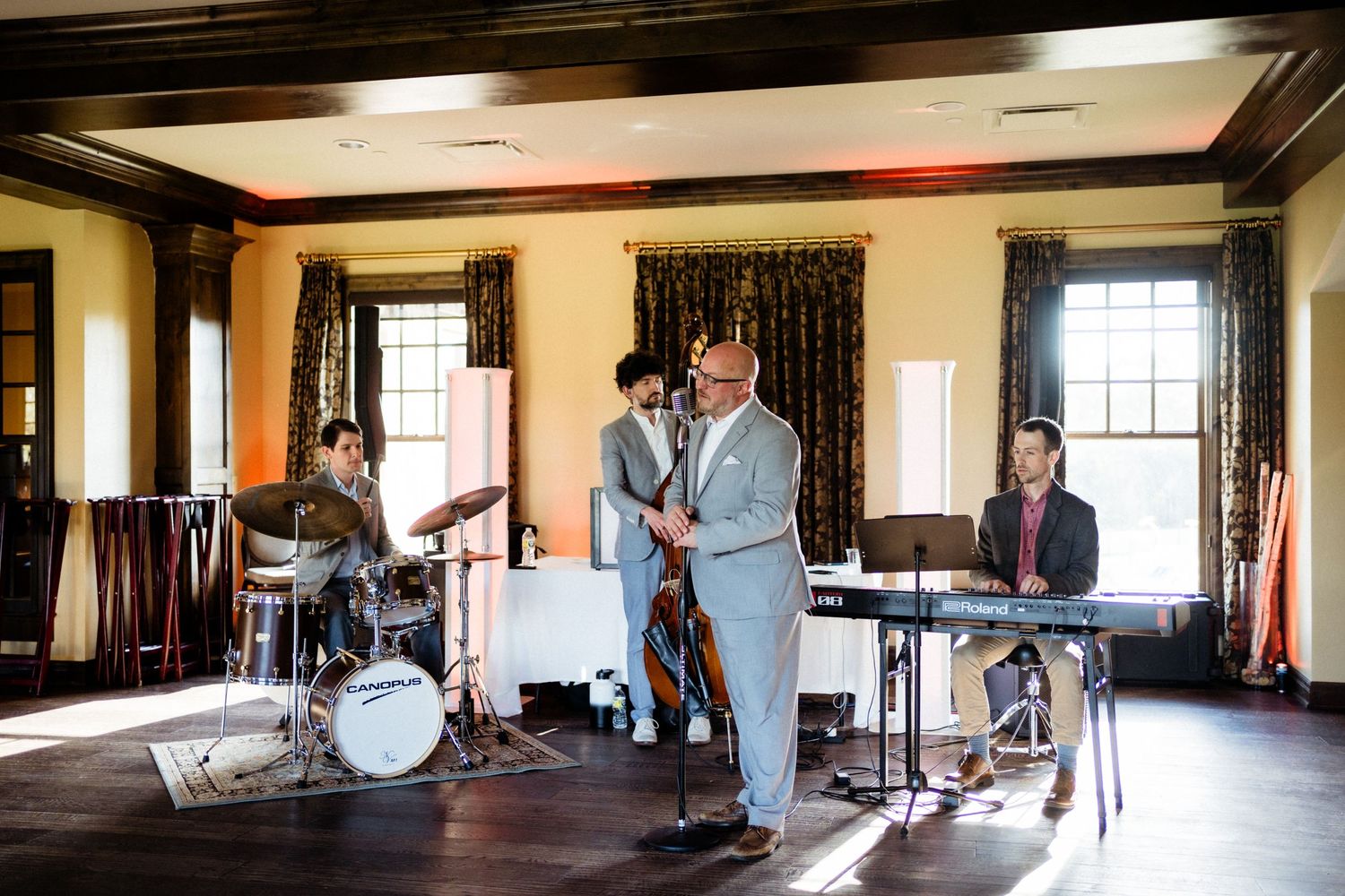 Musicians performing at an indoor wedding reception in a room with dark wooden trim.