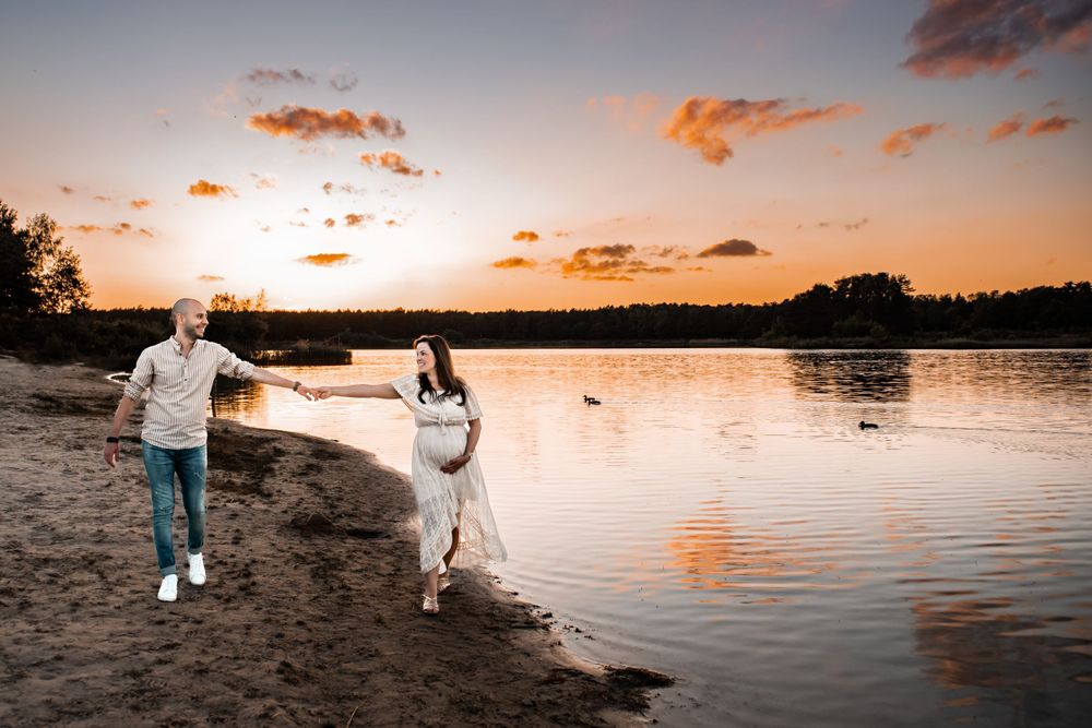 Zwangerschapsshoot in een prachtige setting met een warme zonsondergang en reflectie in het water