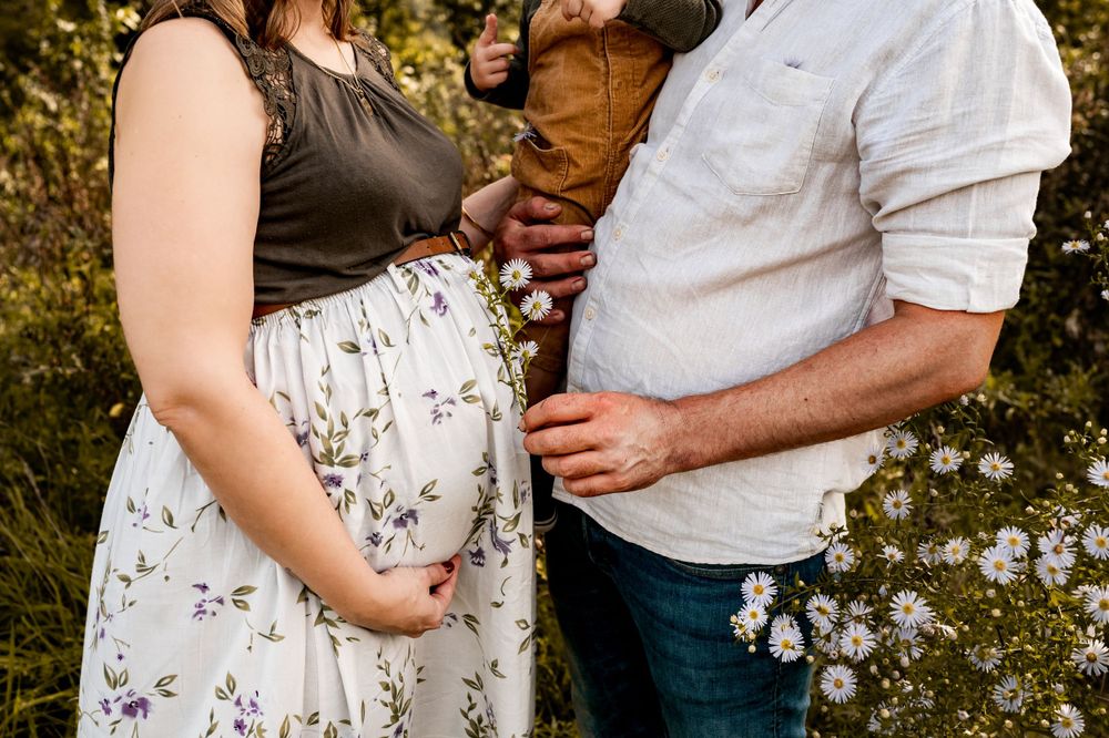 Fleurige zwangerschapsfoto van een gezin van drie met bloemetjes