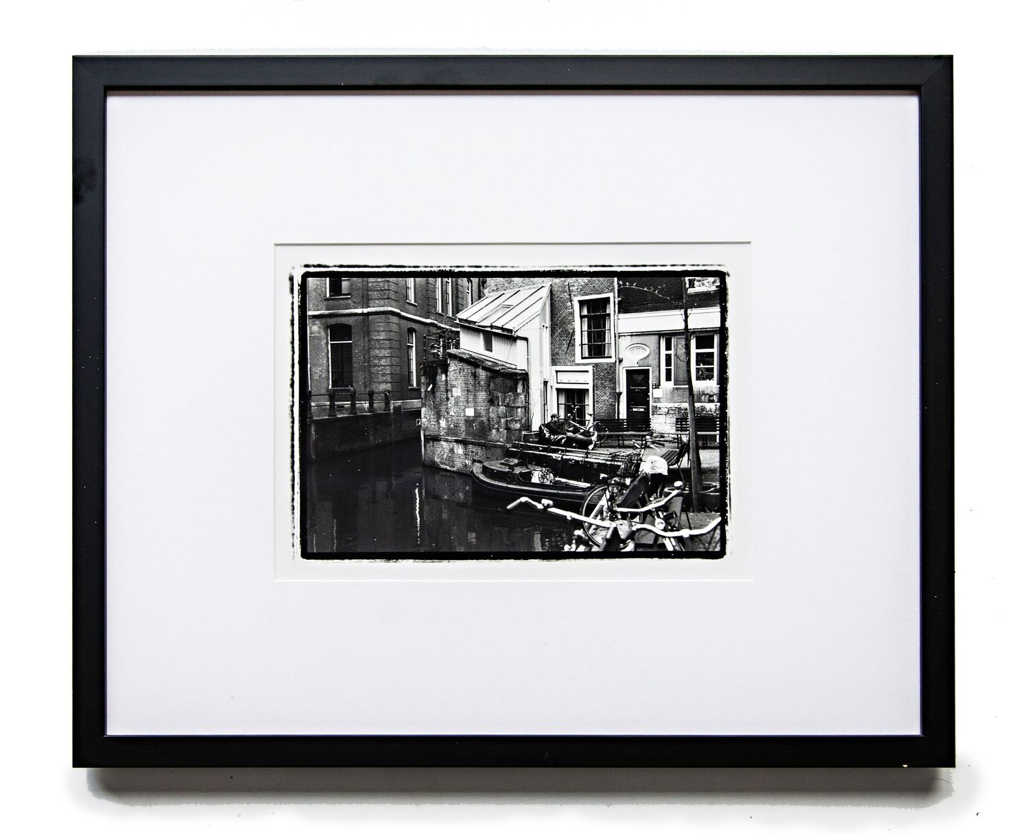 Black and white urban street scene photograph displayed in a simple black frame with white matting.