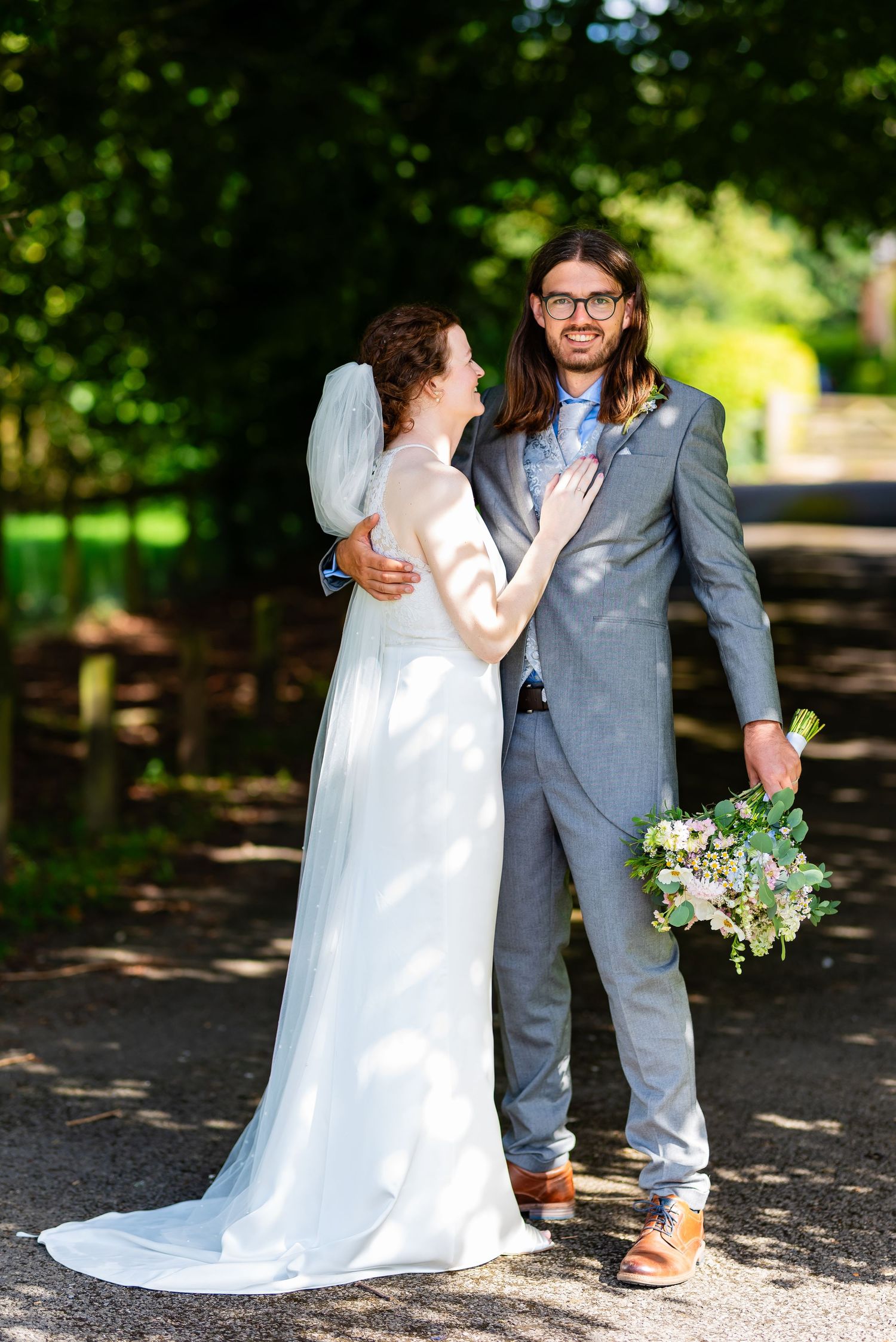 Romantic wedding portrait of couple embracing outdoors in formal attire.