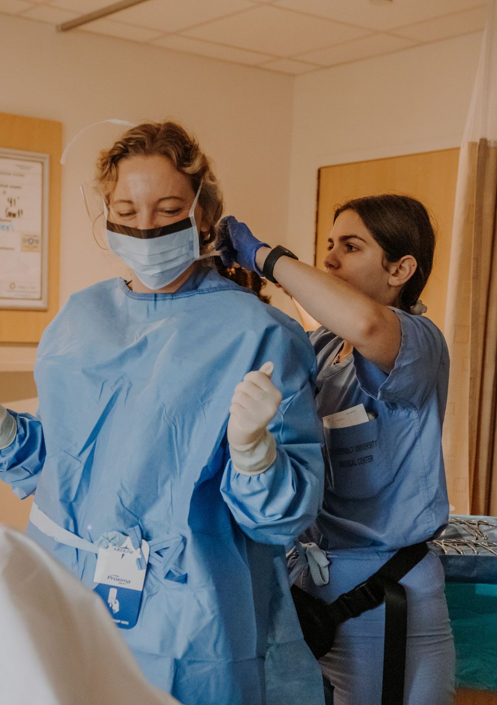 Healthcare workers in blue protective gear preparing for a medical procedure.