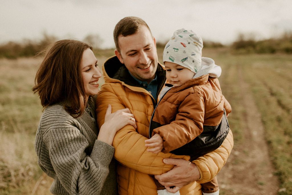 A warm autumn outdoor family photoshoot in a golden field at sunset.