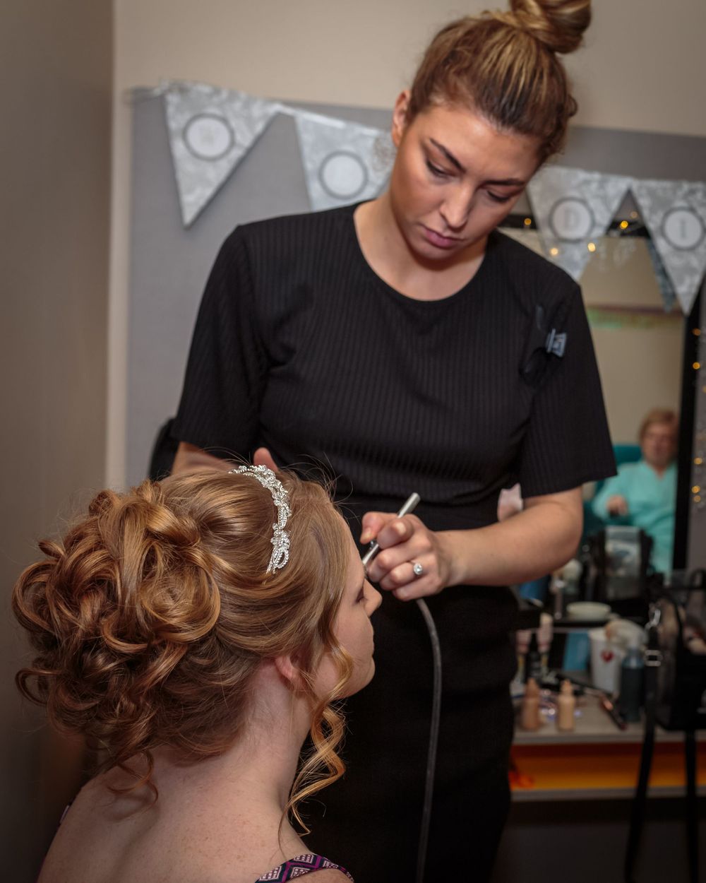 bride has her makeup air brushed on by the make up artist