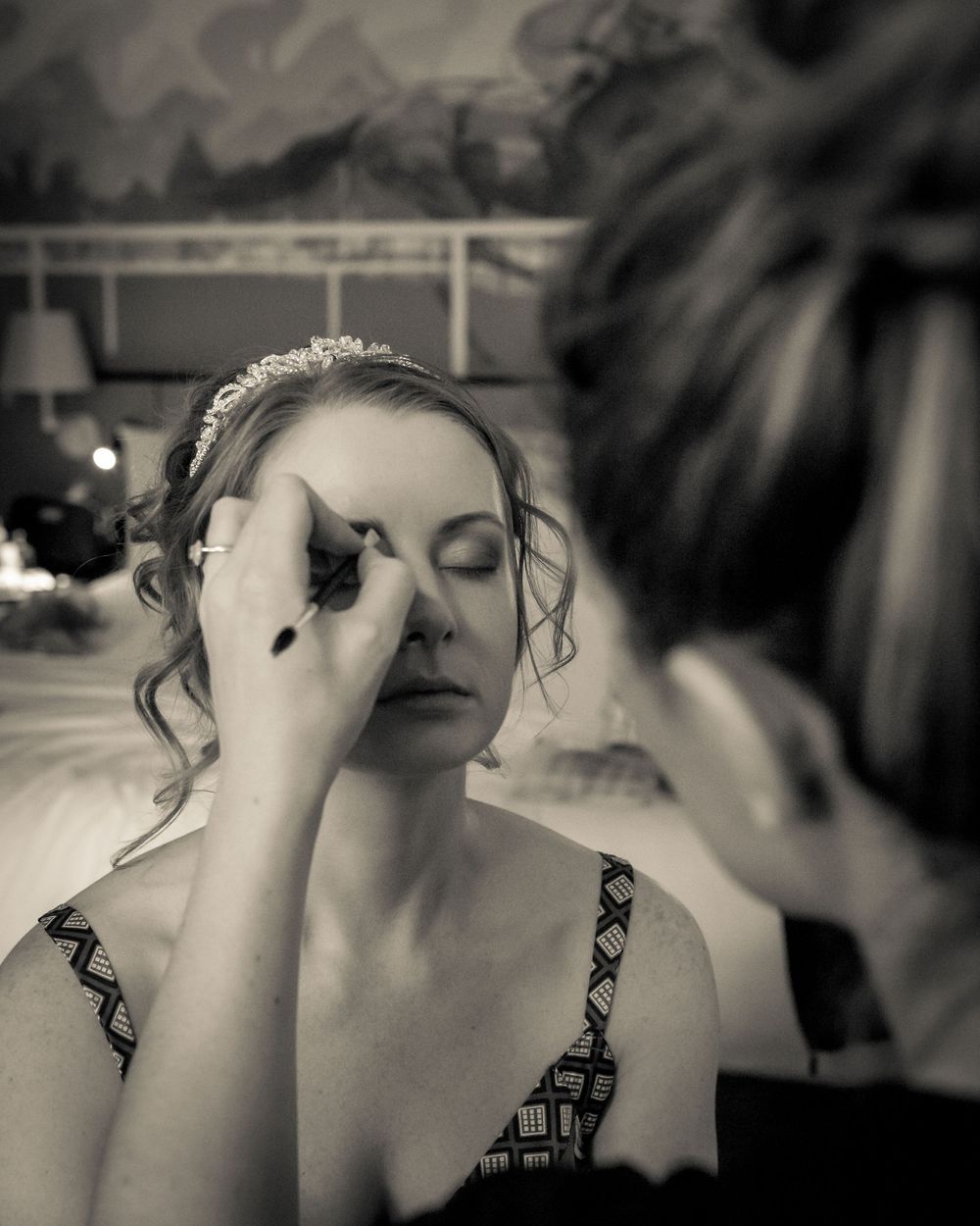 bride has her eye makeup touched up by the mua