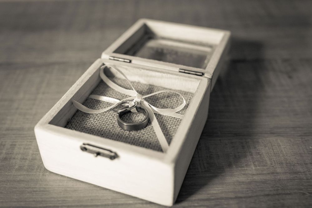 bride and grooms wedding rings in a small wooden ring box