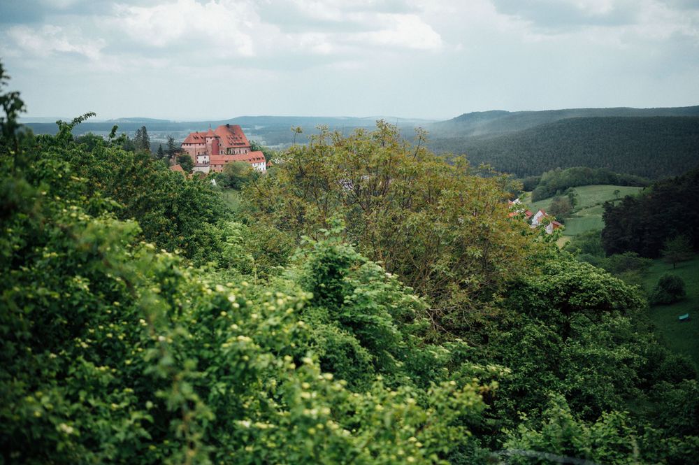 A scenic mountain landscape view with a red building visible among lush green vegetation.