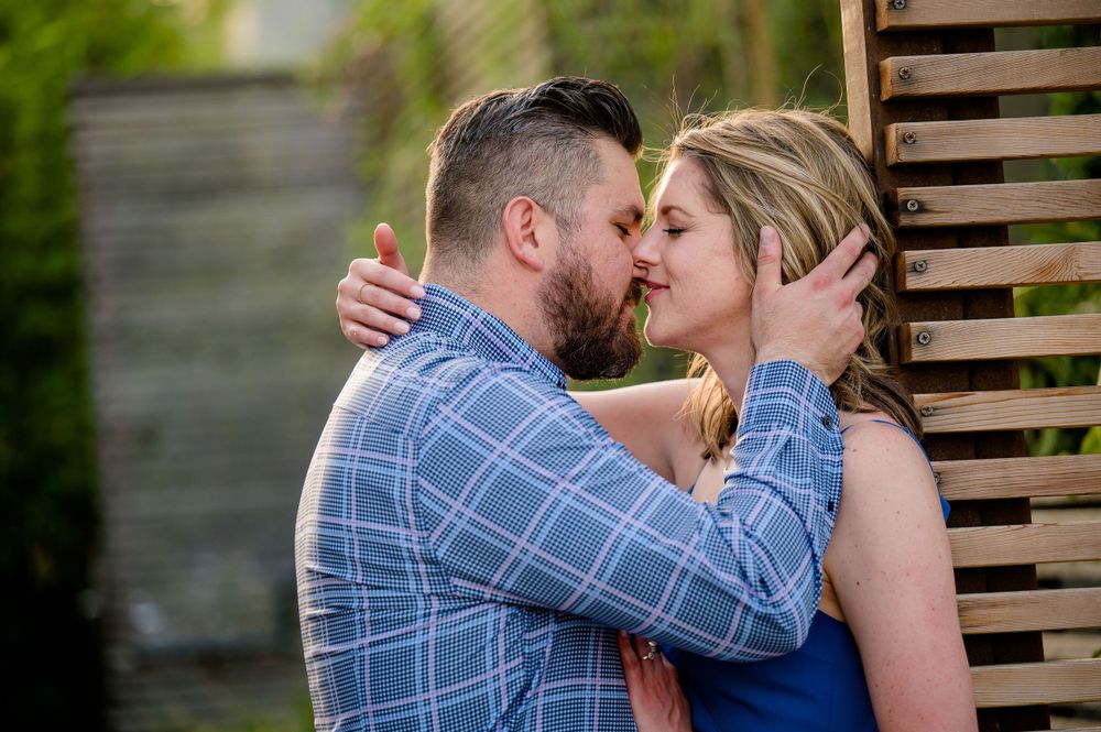Romantic couple sharing an intimate kiss in front of wooden slats.Congress Avenue Engagement session Austin
