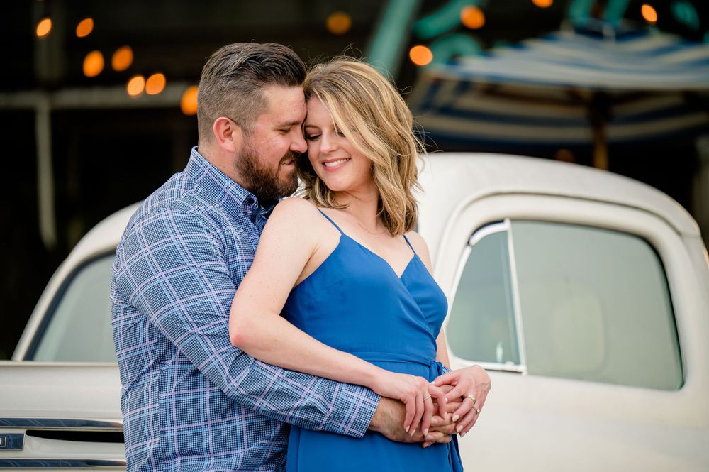 Romantic couple embraces near classic vintage car during evening photoshoot.Congress Avenue Engagement session Austin
