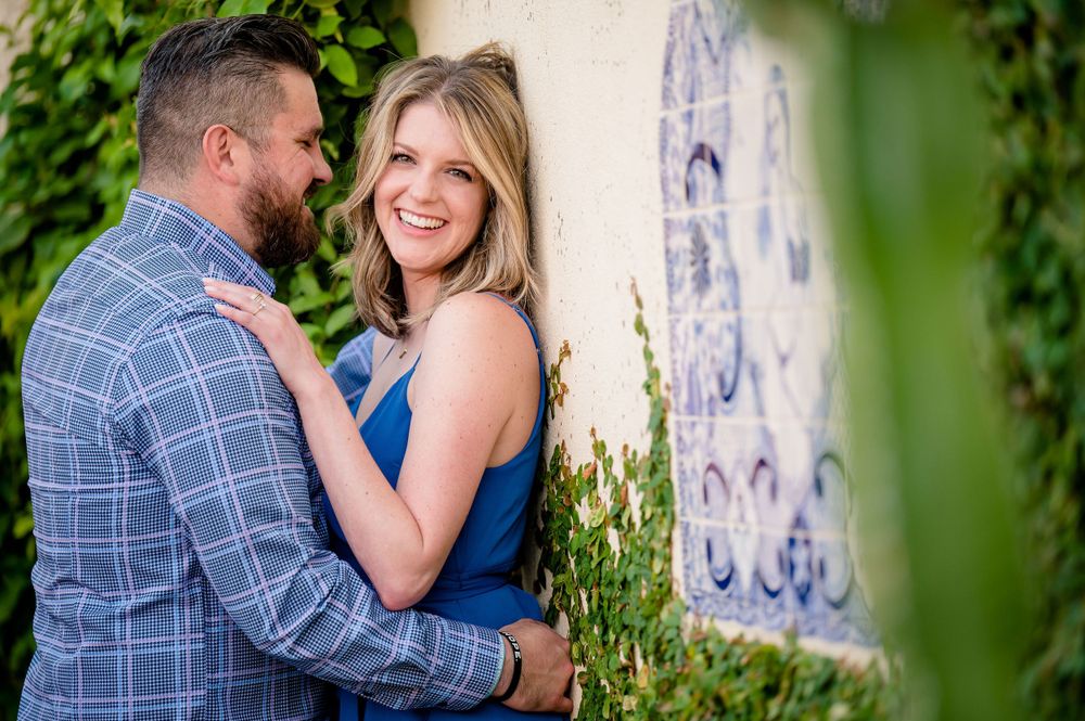 A couple shares a tender moment against a white wall with blue tile accents.Congress Avenue Engagement session Austin