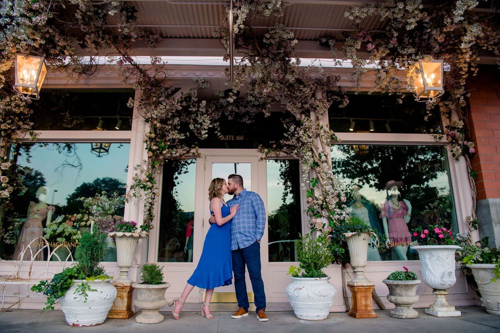 Couple embraces under an elegant archway decorated with greenery and lanterns.Congress Avenue Engagement session Austin
