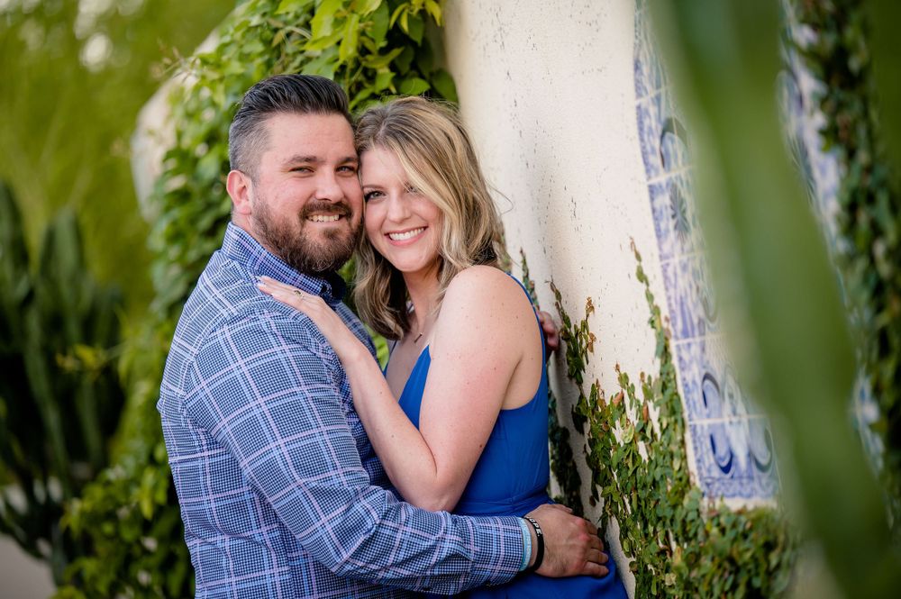 A couple shares an intimate moment in a garden setting with leafy green foliage.Congress Avenue Engagement session Austin