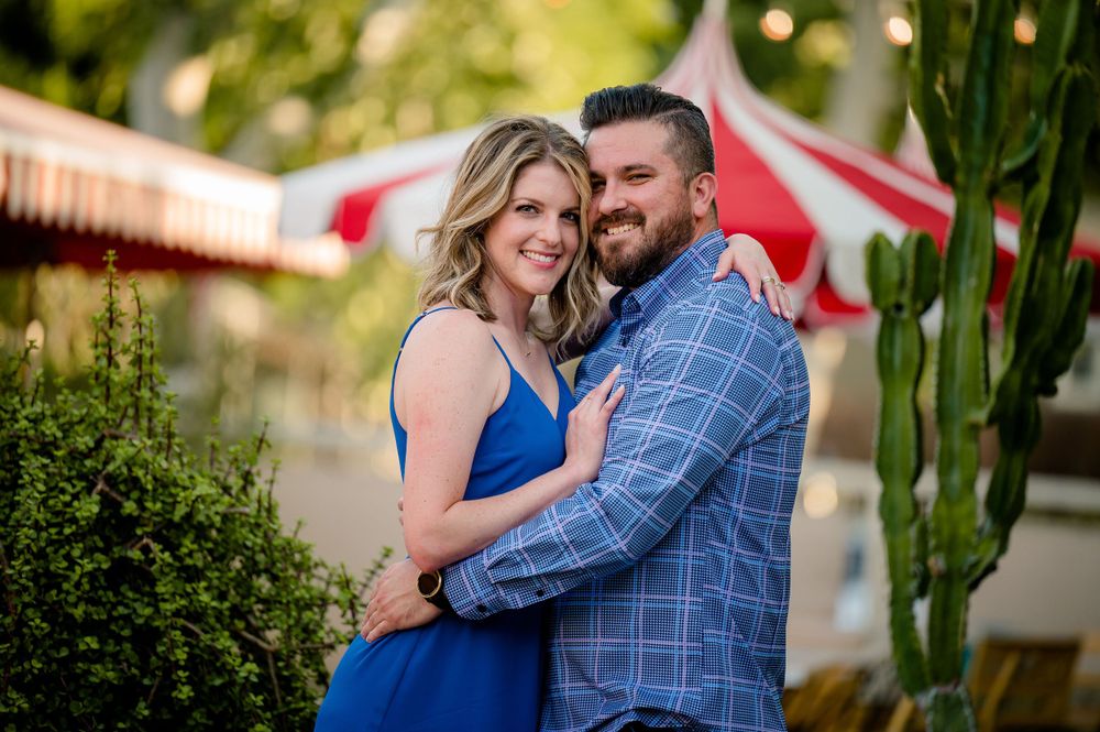 Couple embracing outdoors with red and white striped umbrella in background.Congress Avenue Engagement session Austin