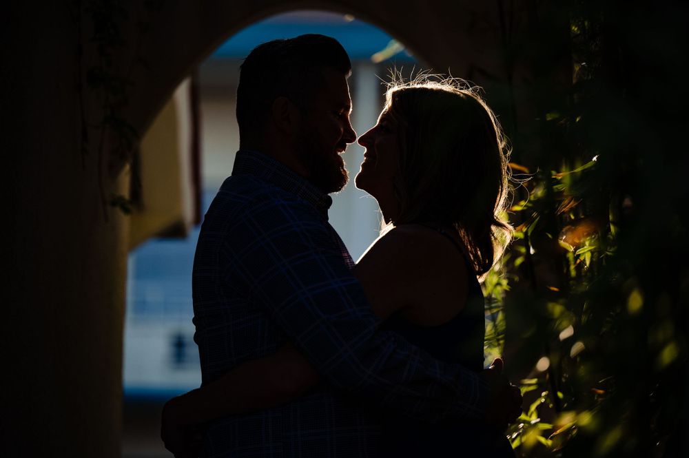 Silhouetted couple sharing intimate moment through archway.Congress Avenue Engagement session Austin