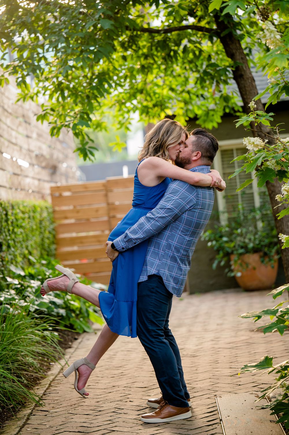 Couple embracing on garden path with green foliage overhead.Congress Avenue Engagement session Austin
