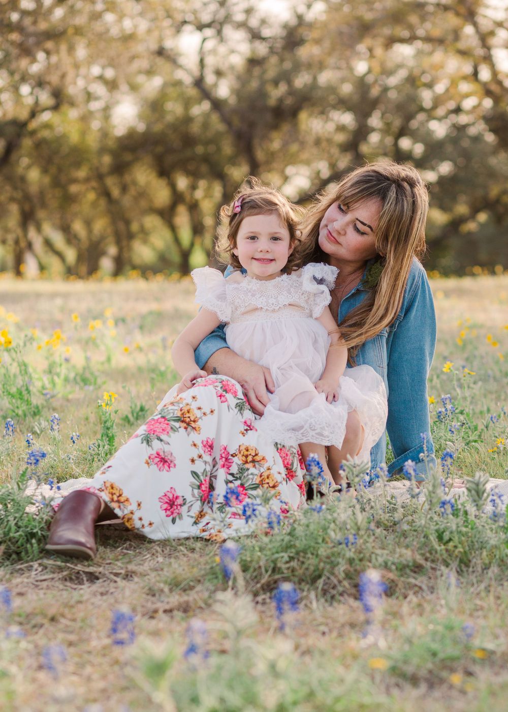 Family sharing tender moments while sitting in field of spring wildflowers.