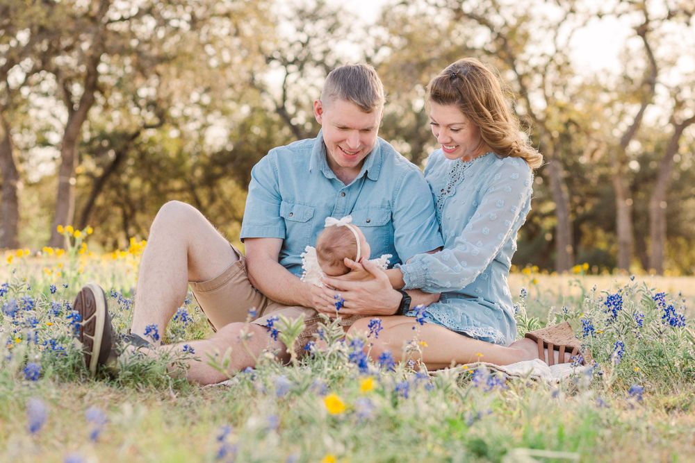 Family lounges together in field of spring wildflowers during sunset.