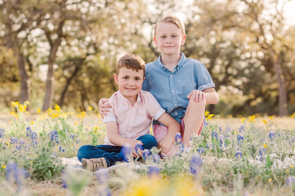 Family poses together among spring wildflowers in a sunny field.
