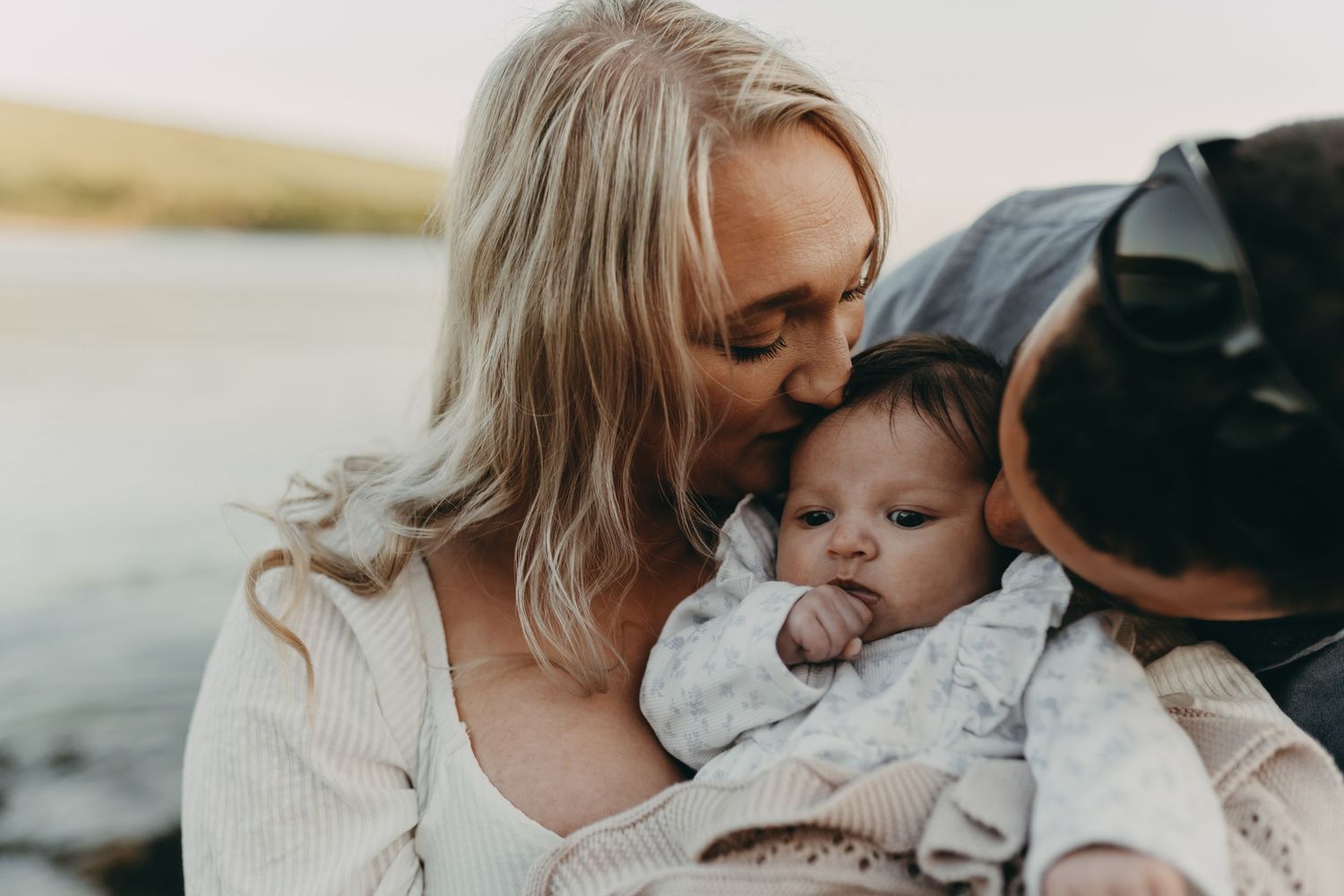 Close-up portrait of tender family moment on beach at sunset.