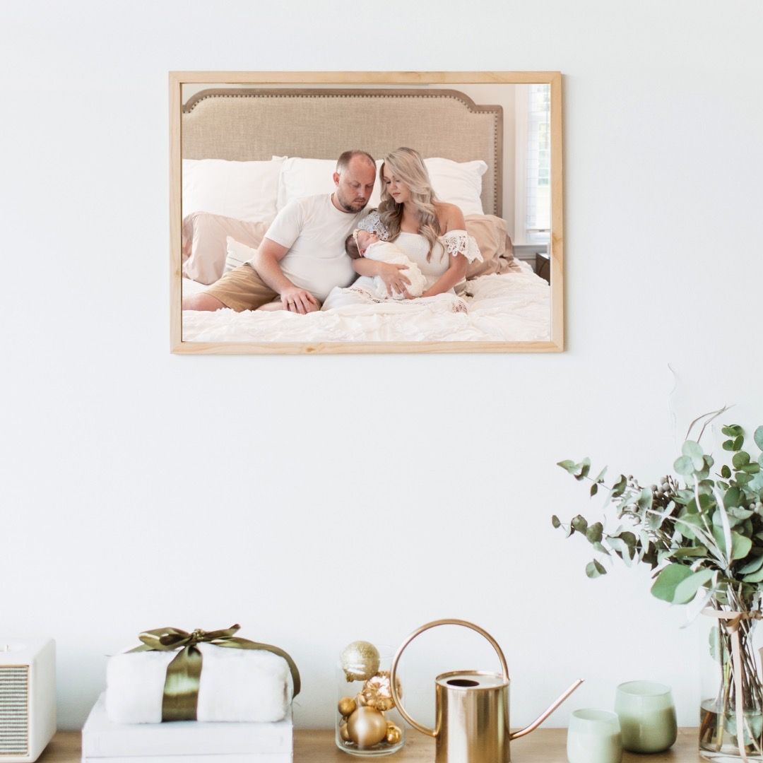 Clean modern home decor with framed family photograph on white wall, styled with golden teapot and greenery.