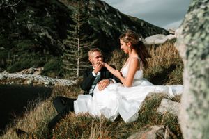 Wedding couple sharing intimate moment on rocky mountain overlook.