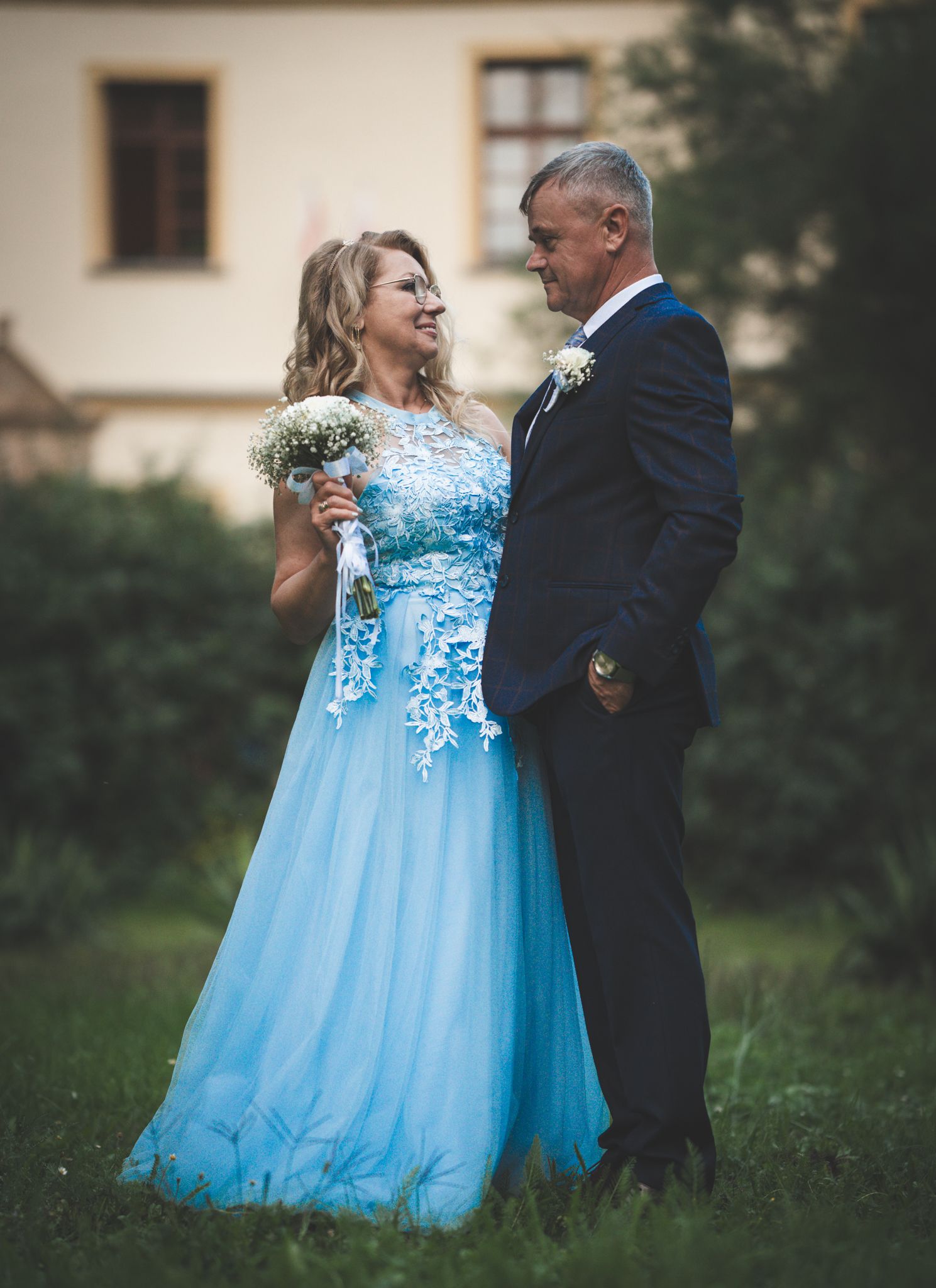 Romantic wedding portrait outdoors with bride in flowing blue gown with lace details.
