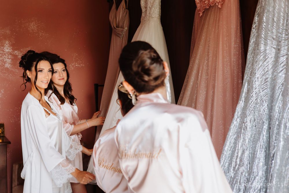 Bridesmaids in white robes gather during morning wedding preparations.