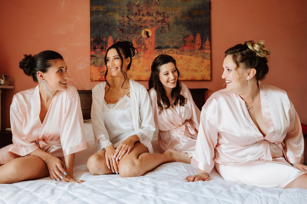 Wedding party in silk robes shares joyful moment during pre-ceremony preparations.