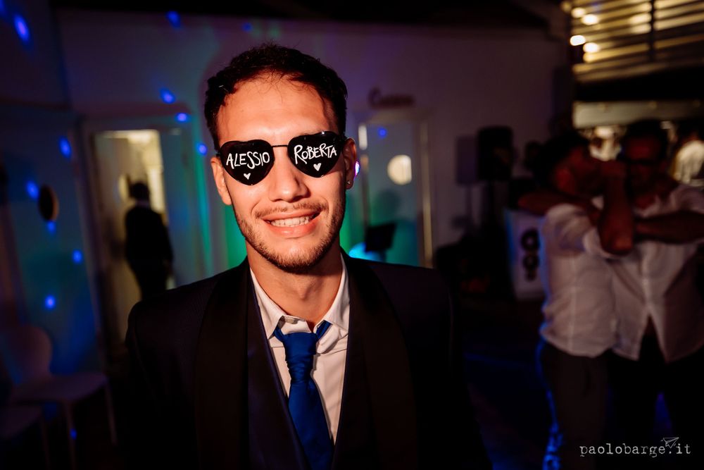 A guest enjoying the wedding party while wearing sunglasses with party lights in the background.