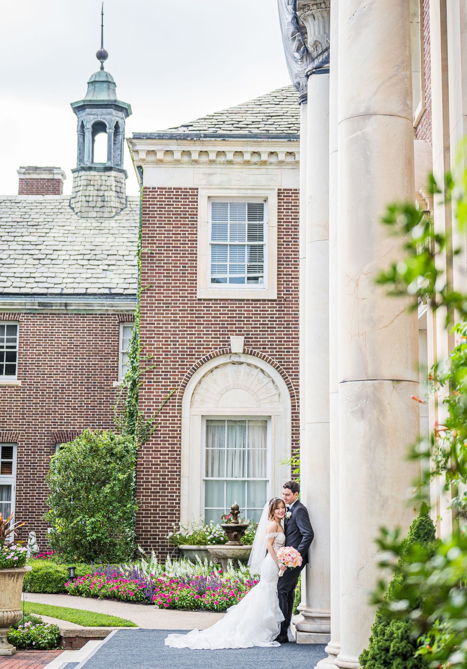 A couple leaning against the tall columns of the venue. NYIT