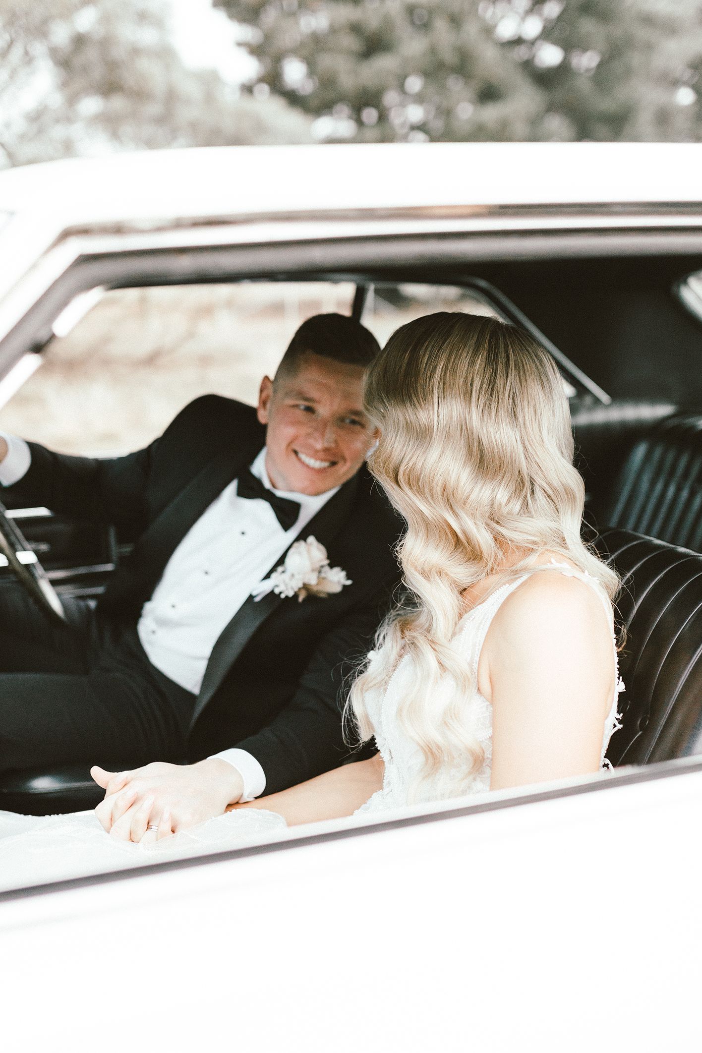 A couple sitting in a vintage car sharing a romantic moment during their wedding photoshoot.