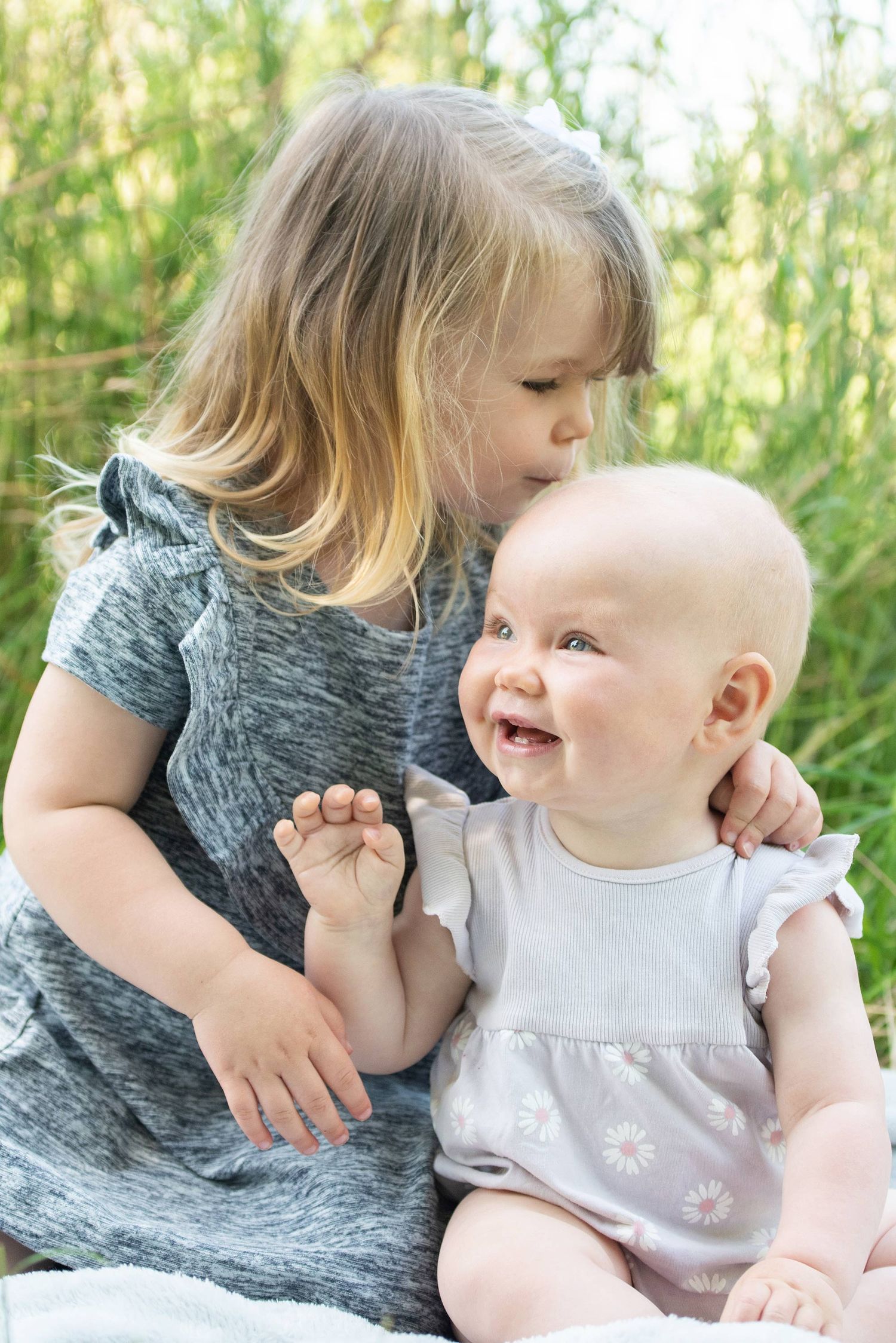 Two young children share tender moment outdoors in natural setting.