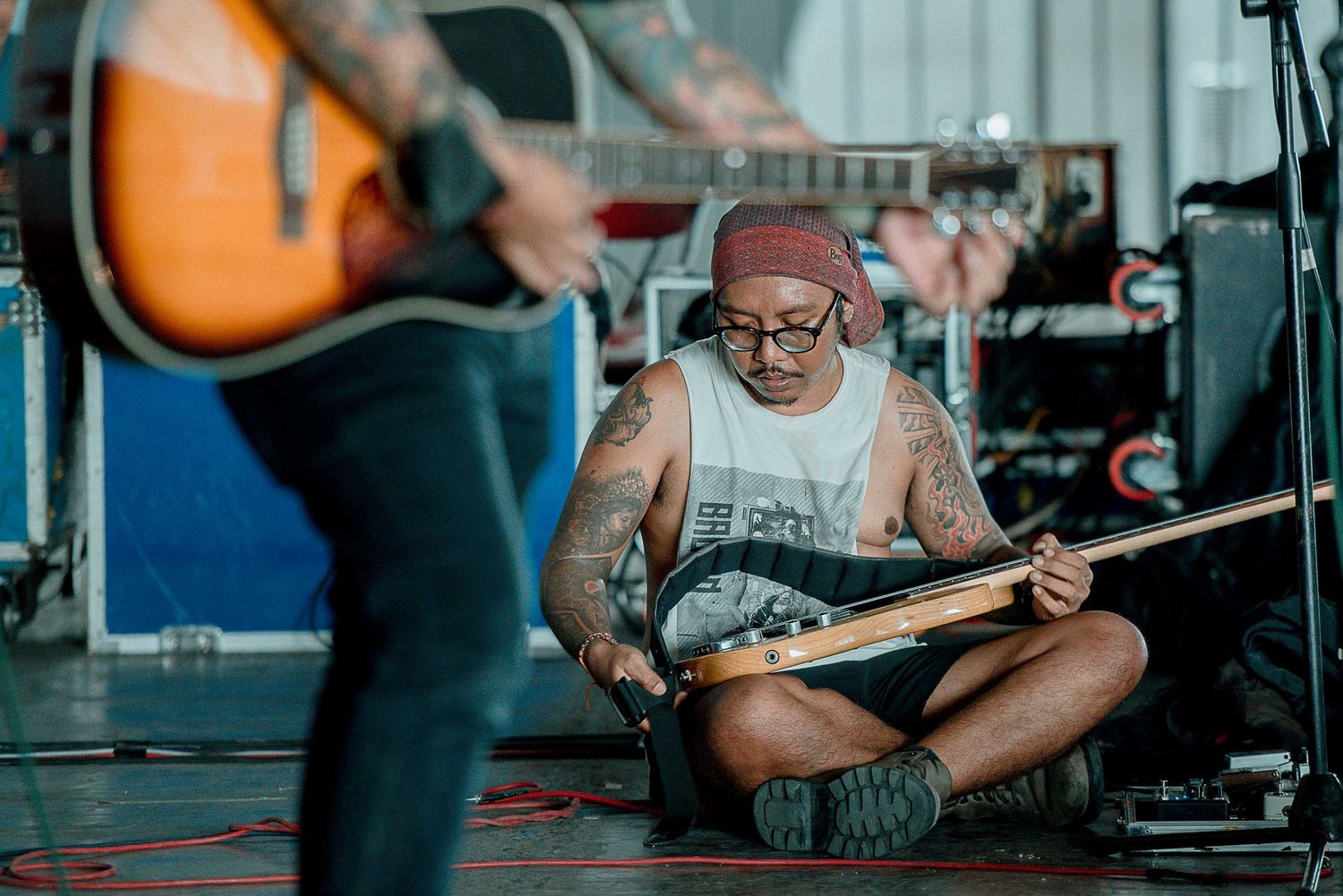 Musicians rehearse with acoustic guitars in a casual studio setting.
