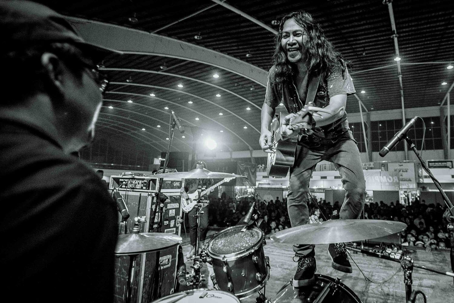 Dynamic black and white shot of musicians performing on stage with dramatic lighting.