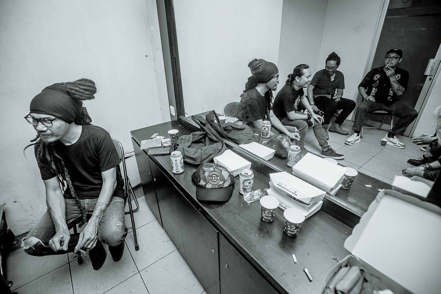 Band members prepare in a cramped backstage dressing room area.