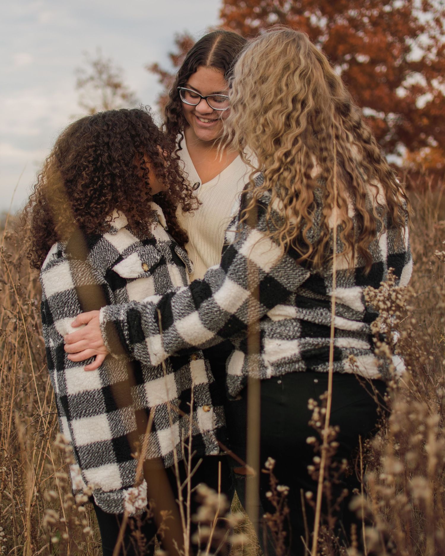 Loving moment between a mother and her two daughters in a field, exchanging glances.