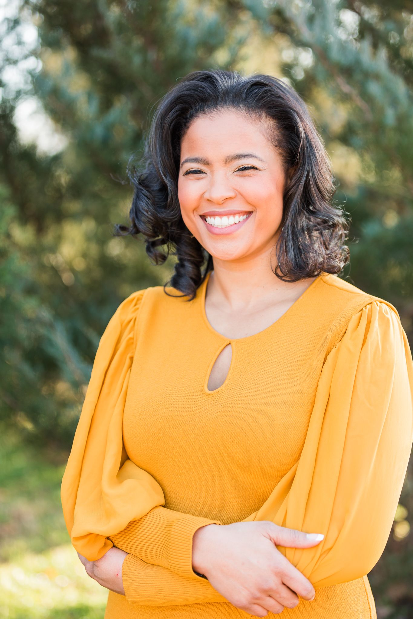 Woman posing outside in yellow dress for headshot