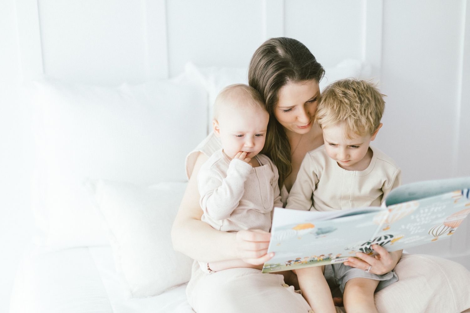 Tender moment of parent reading storybook with children on bed.