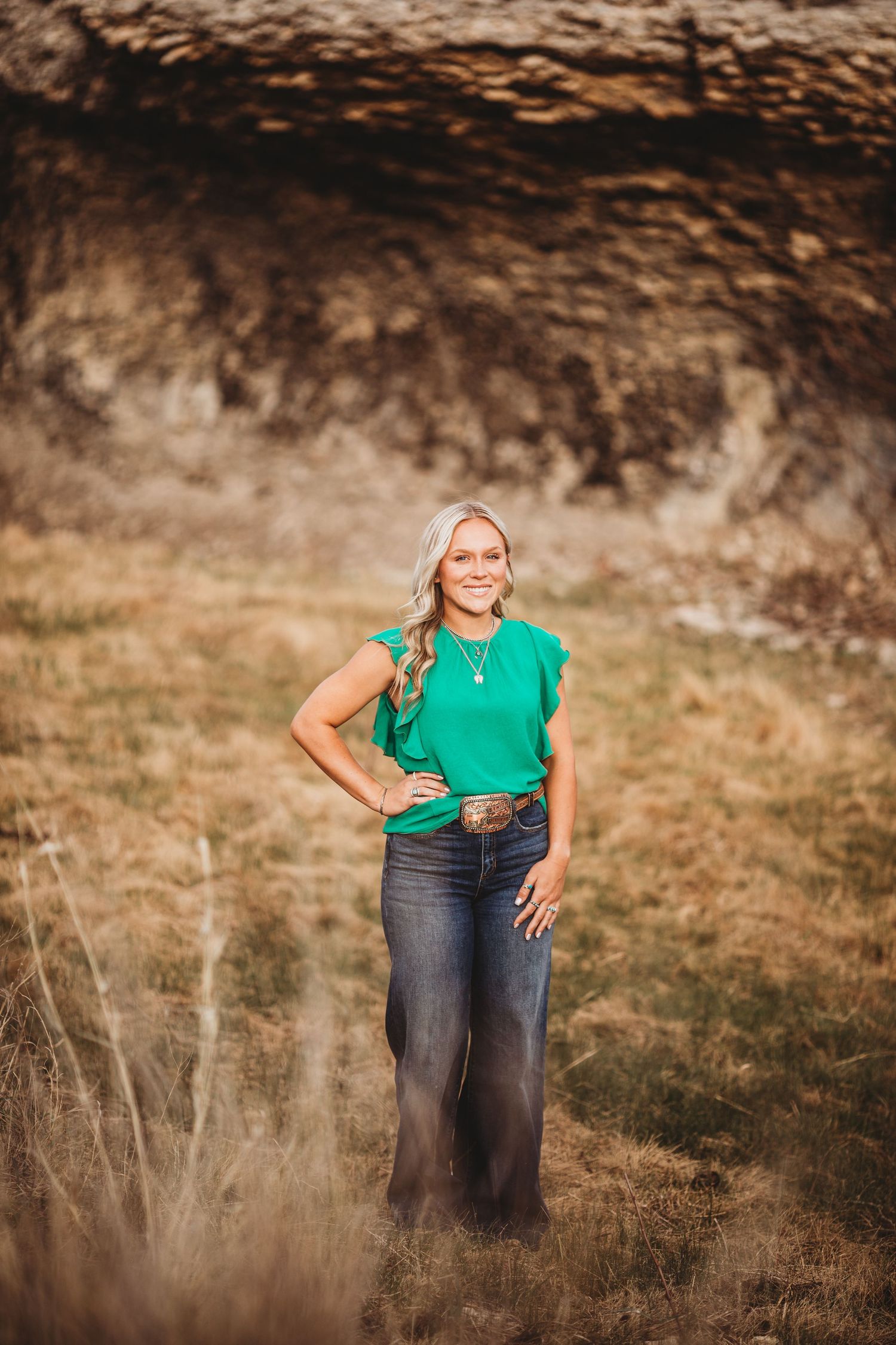 Outdoor portrait in rural setting with mountains and natural textures as backdrop.
