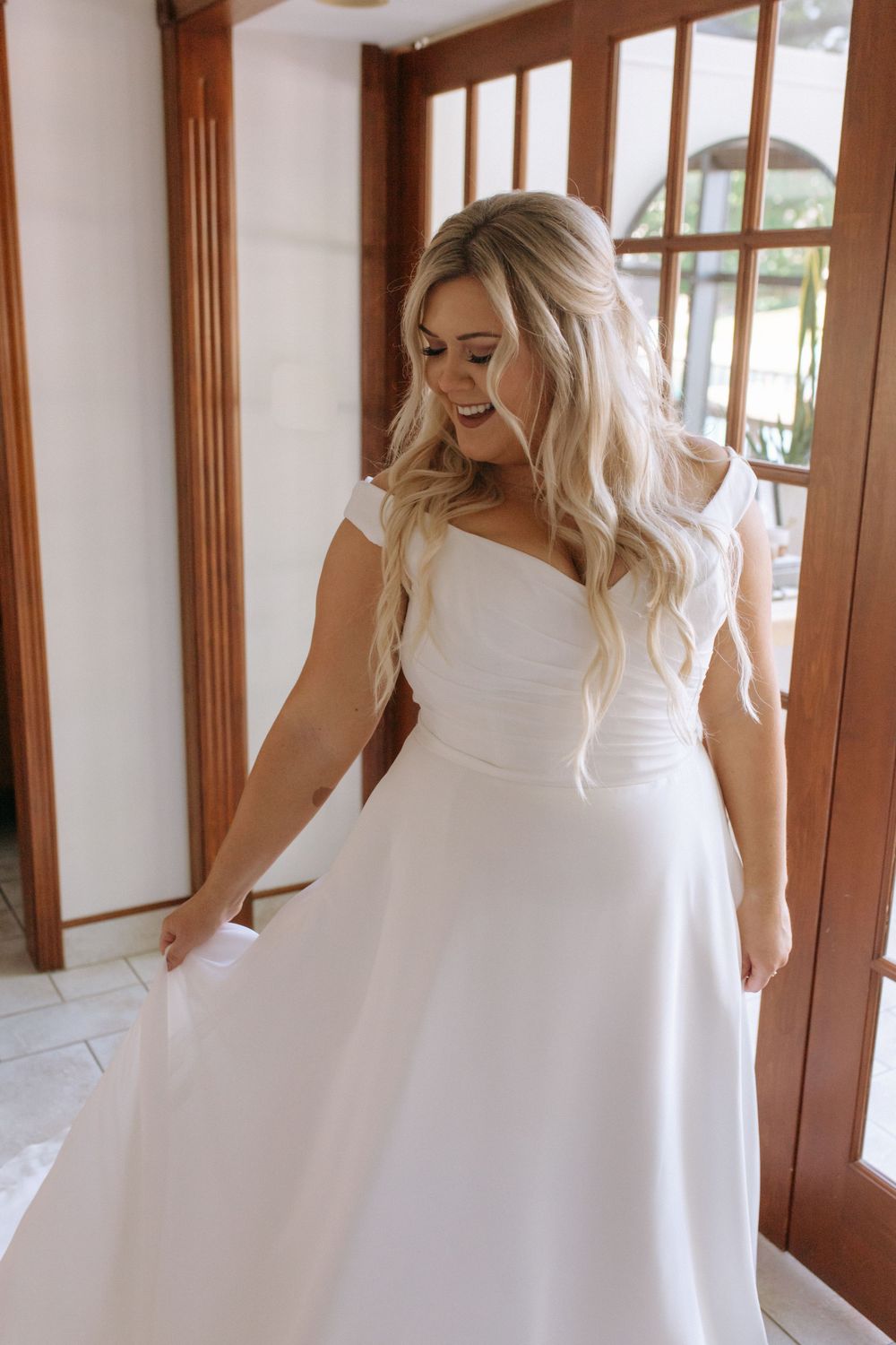 Candid moment of bride admiring her classic A-line wedding gown.