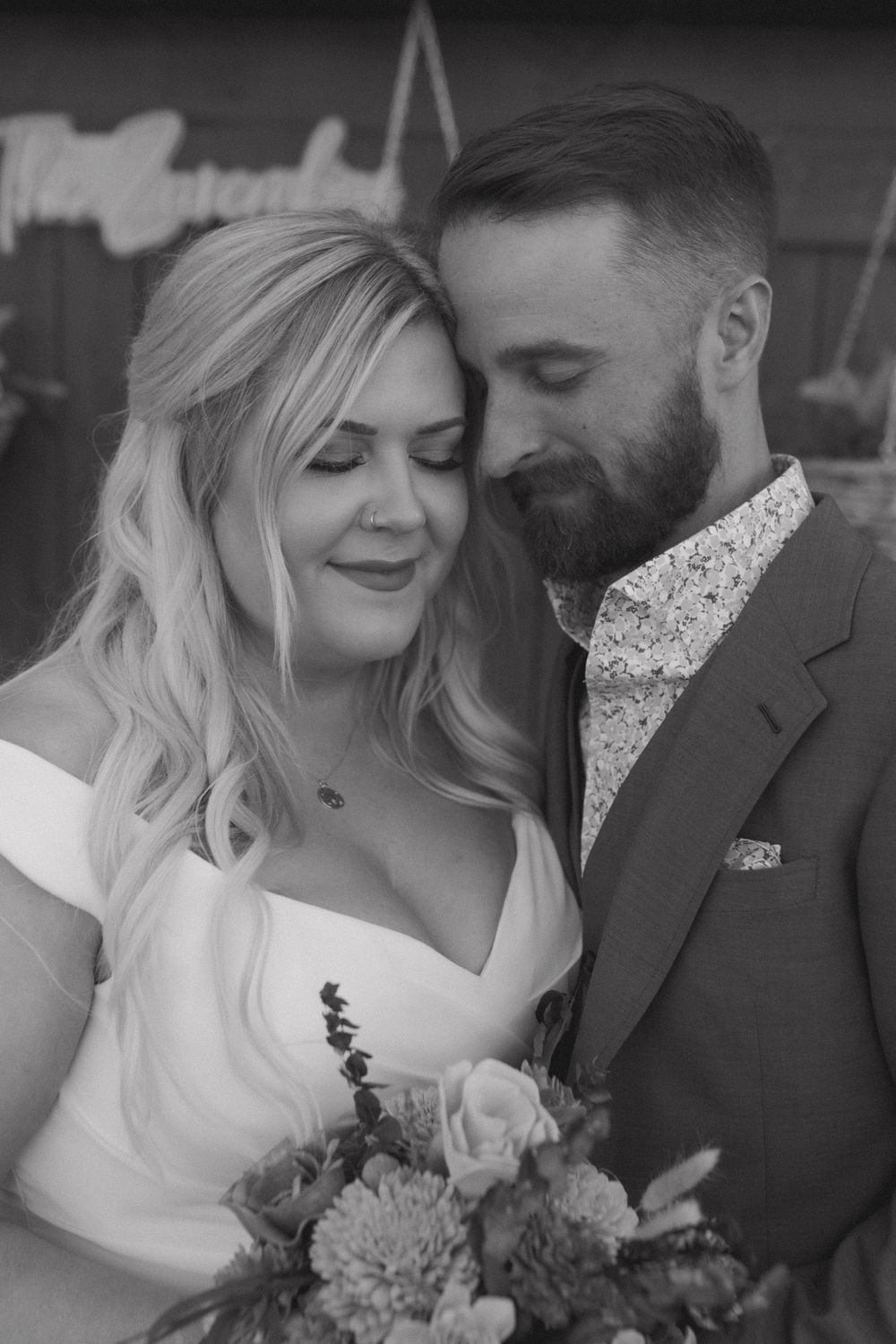 Black and white close-up of tender wedding moment with bride holding floral bouquet.