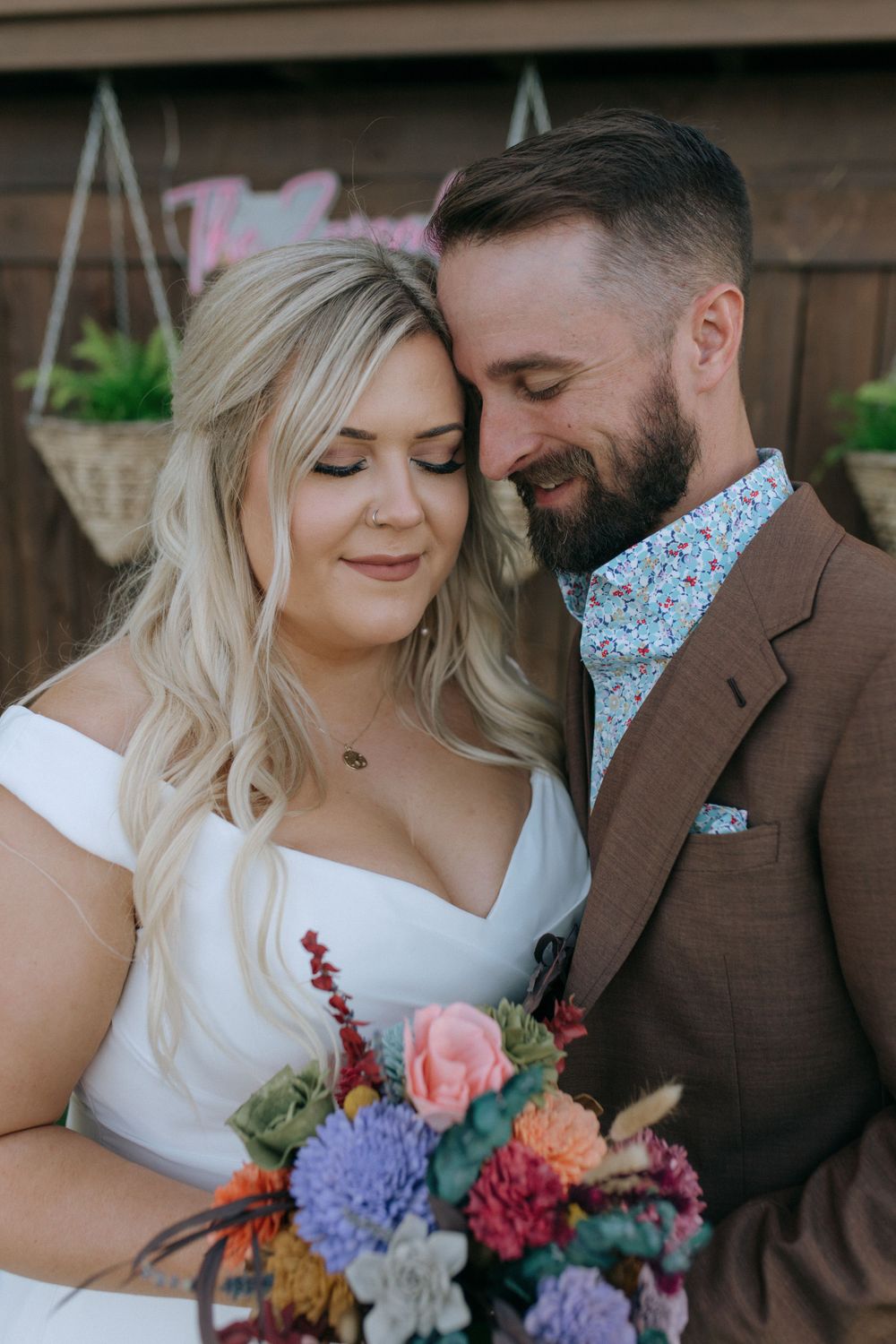 Close-up of happy newlyweds sharing tender moment with vibrant wedding flowers.