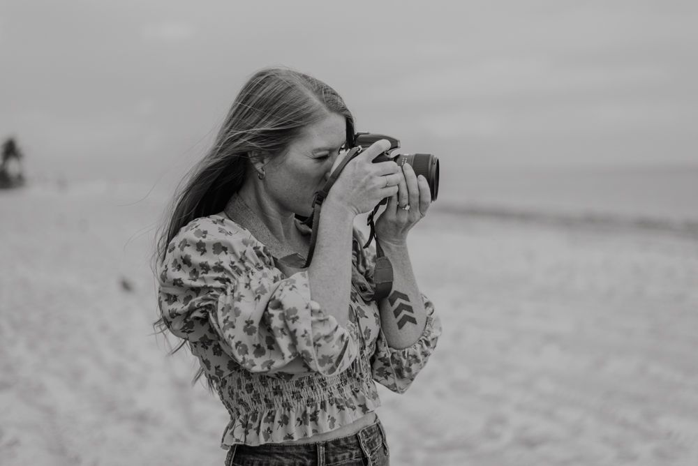 Person with camera photographing on beach in black and white.